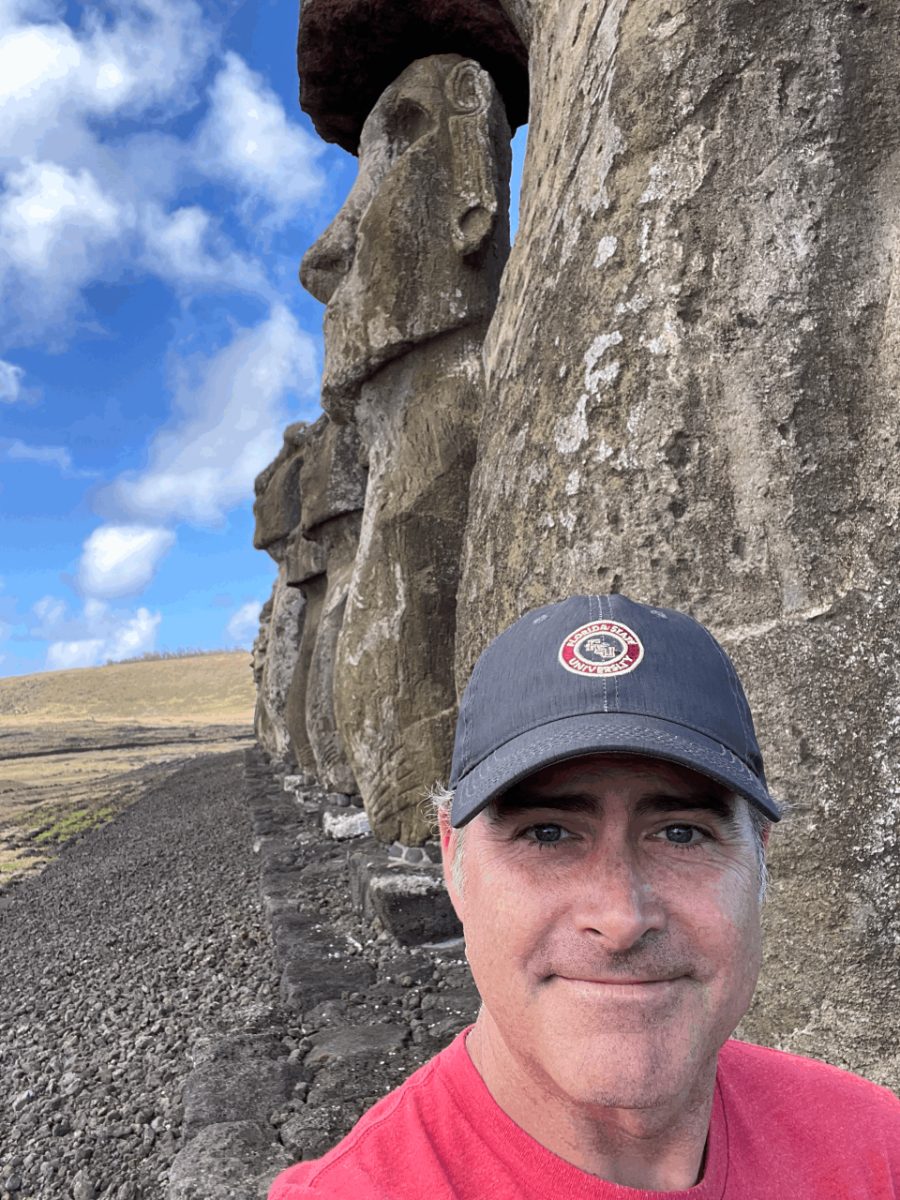 Mark McCoy standing beside a moai statue on Rapa Nui